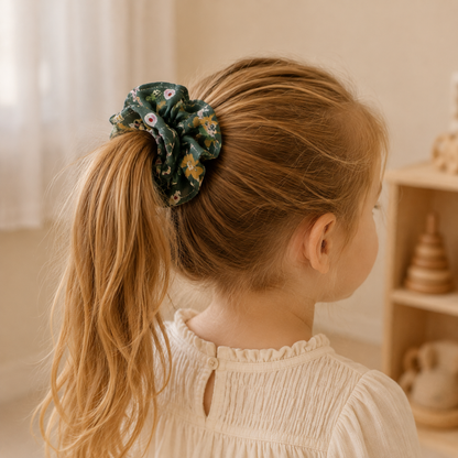 Child wearing the Woodland Bloom forest green floral ruffle scrunchie in a ponytail