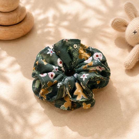 Woodland Bloom forest green floral ruffle cotton scrunchie displayed with wooden toys and a knitted bunny