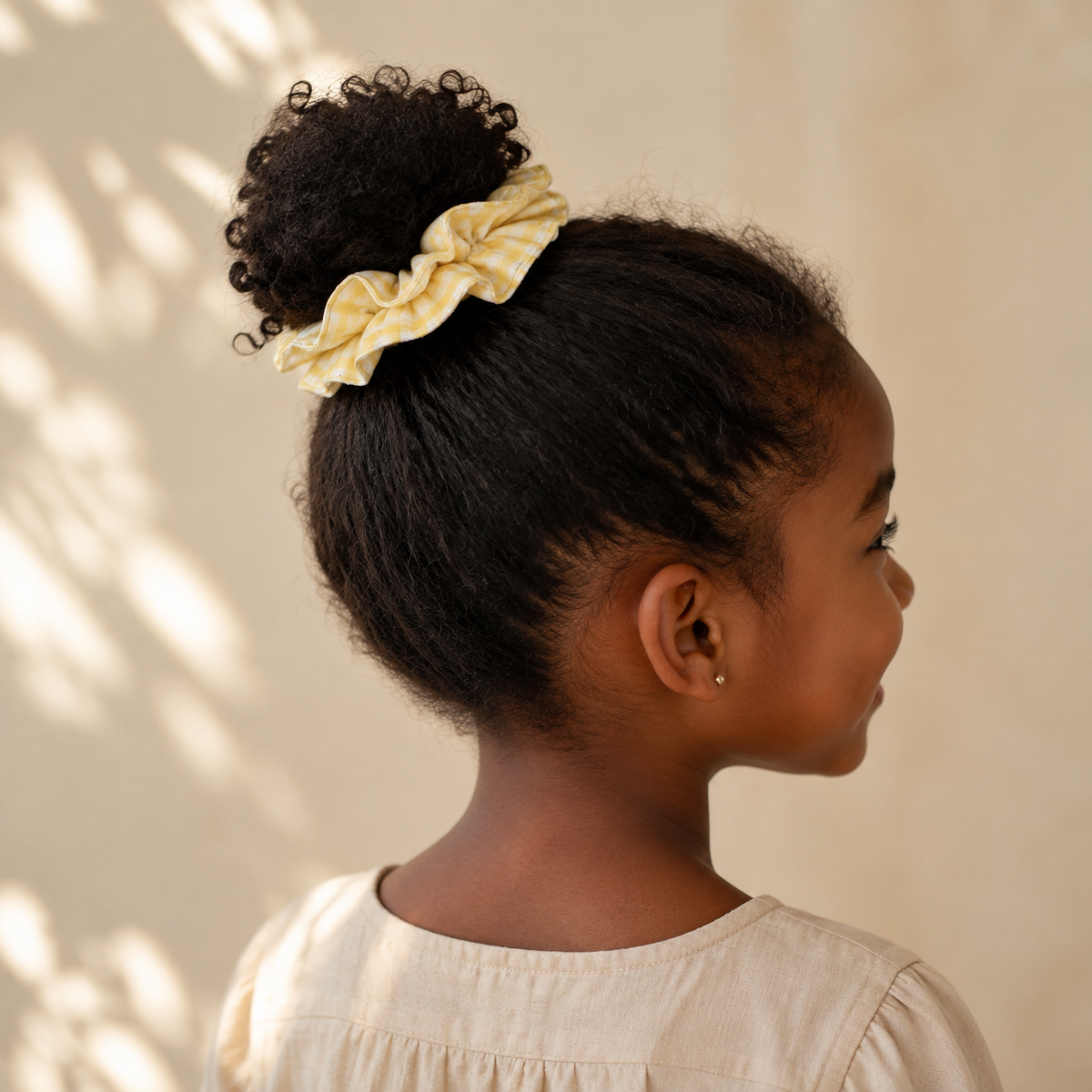 Child wearing the Butter Gingham yellow ruffle cotton scrunchie in a ponytail
