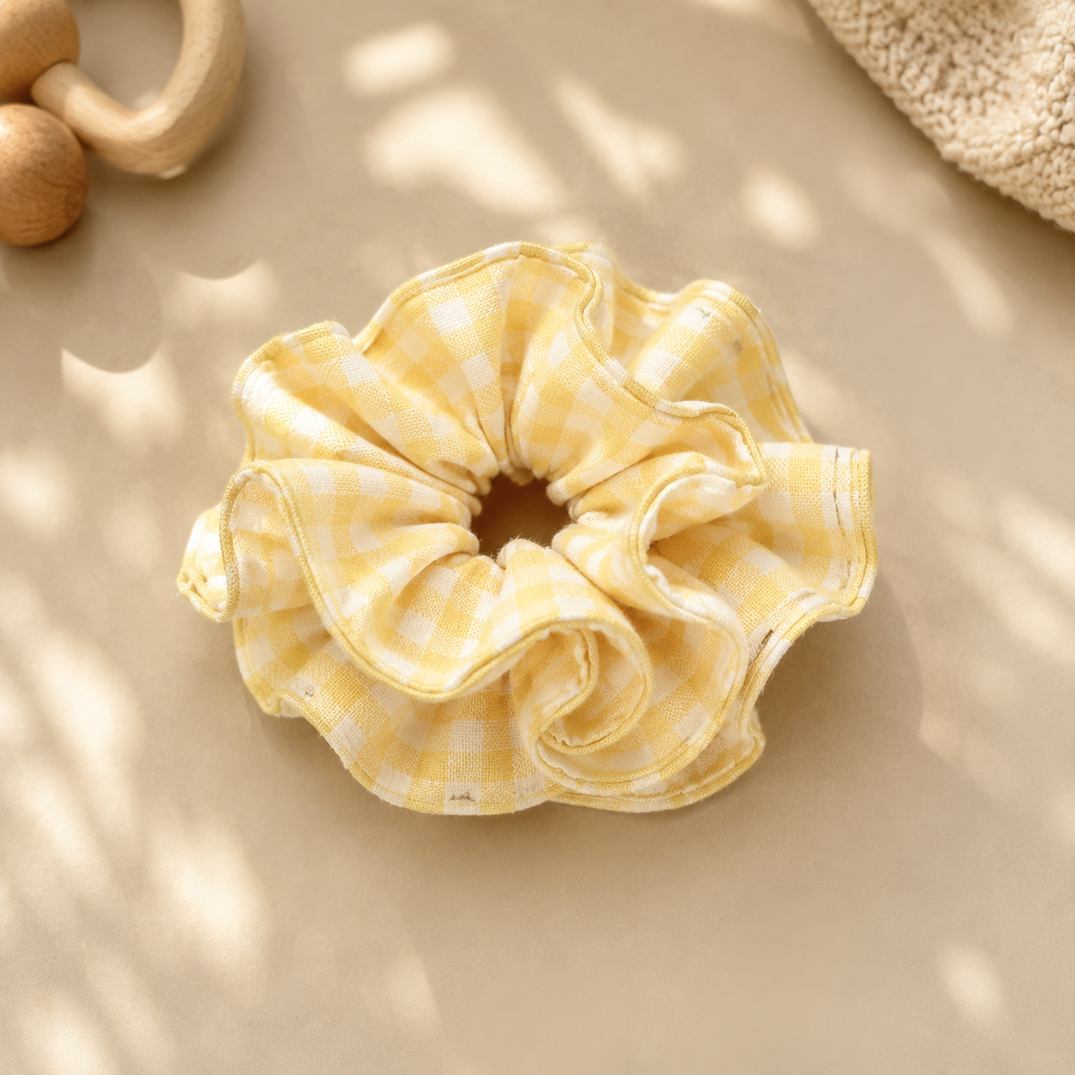 Butter Gingham yellow and white ruffle cotton scrunchie displayed in warm natural light with a wooden baby toy